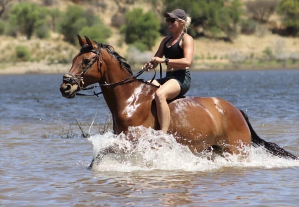 Nicky riding a bay horse through the water